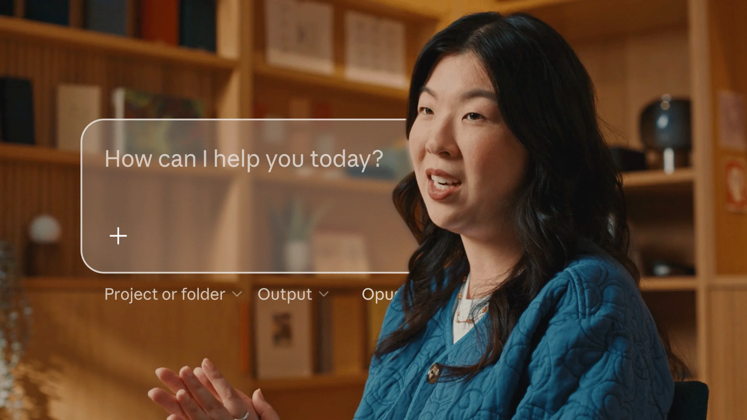 Still from the Claude announcement video, a woman speaking next to the Claude prompt field asking How can I help you today?