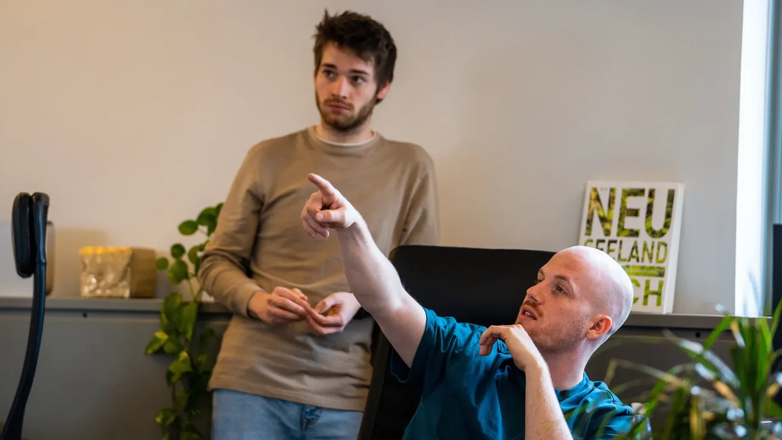 Two Dotbite engineers in the office in Vienna, one seated and pointing at a screen, the other standing behind him and following along