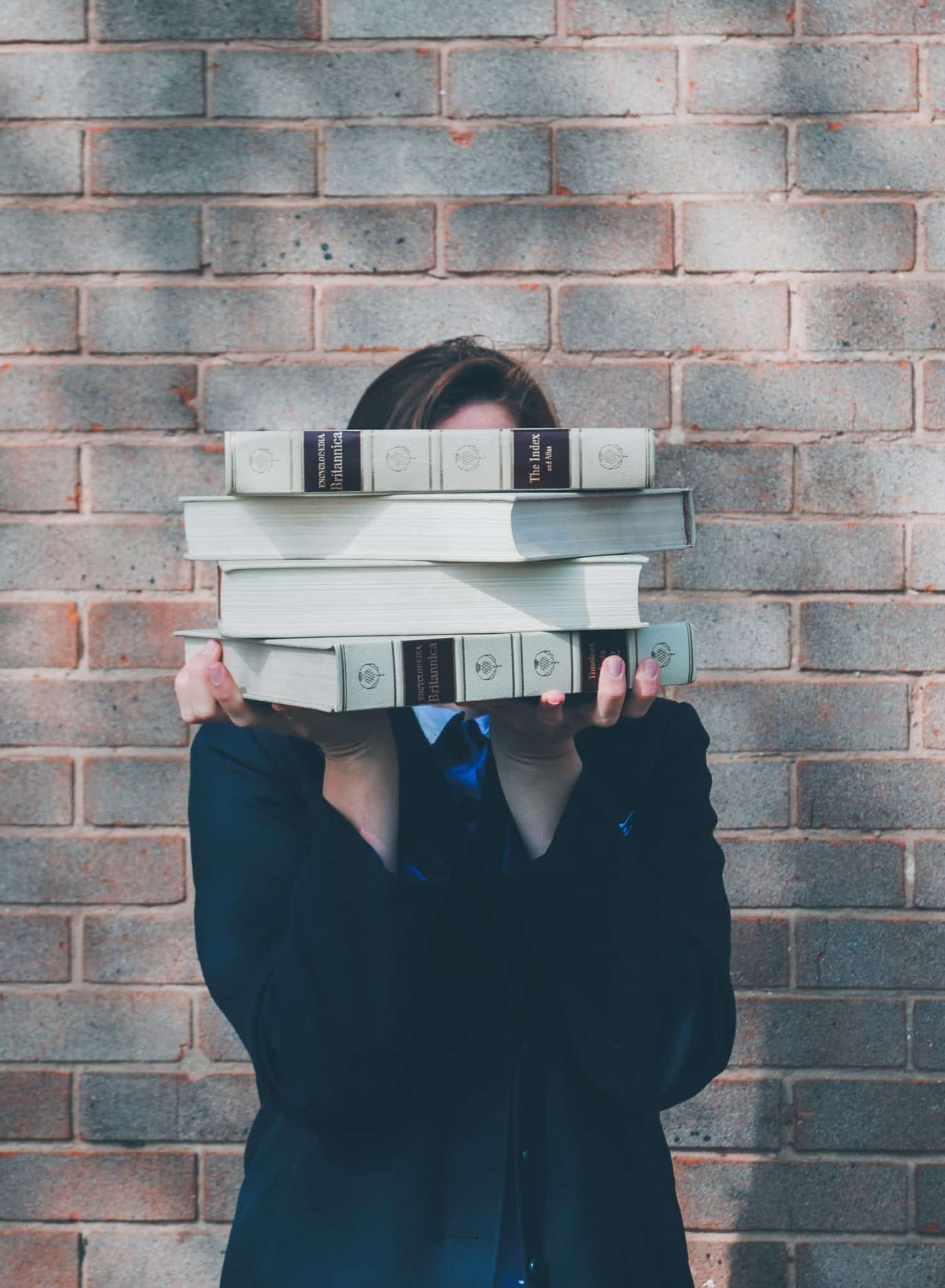 A woman is holding thick books in her hands