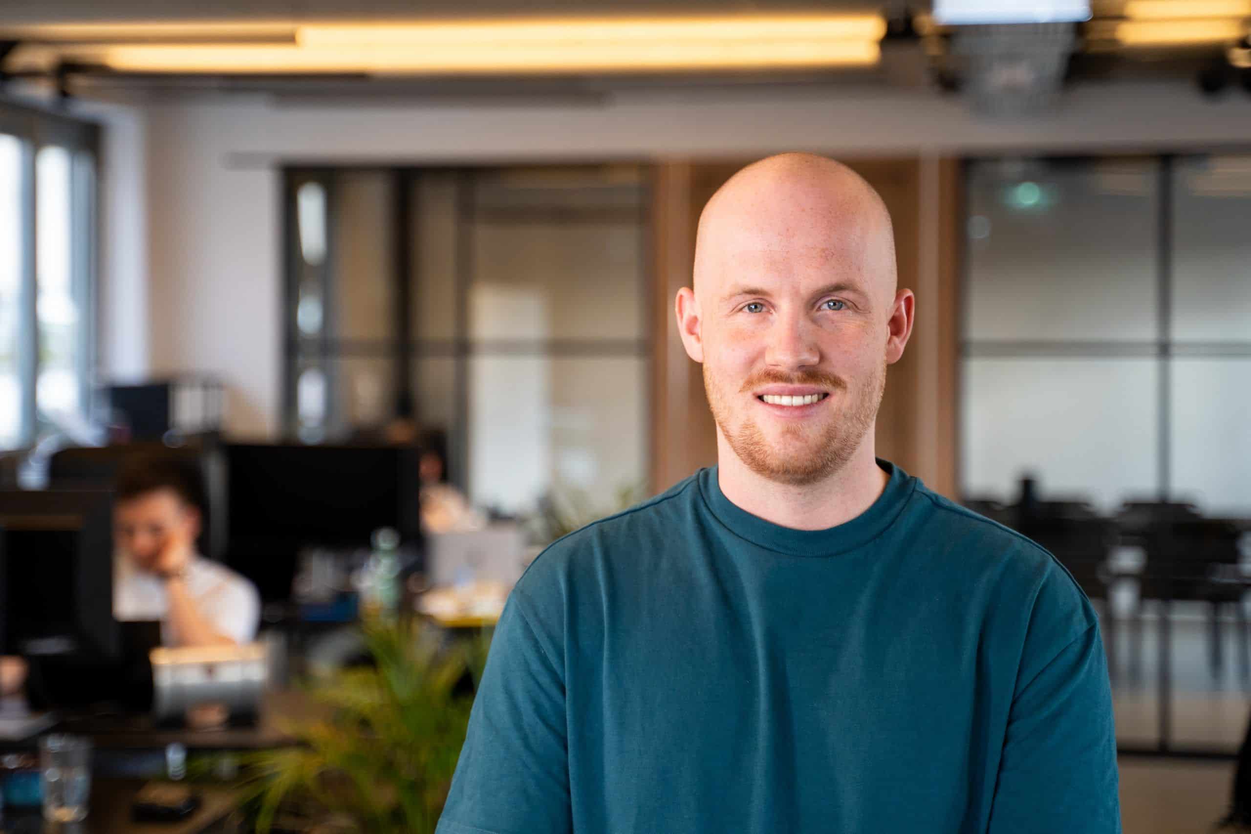 Co-founder Adrian is standing in front of the meeting room and smiling