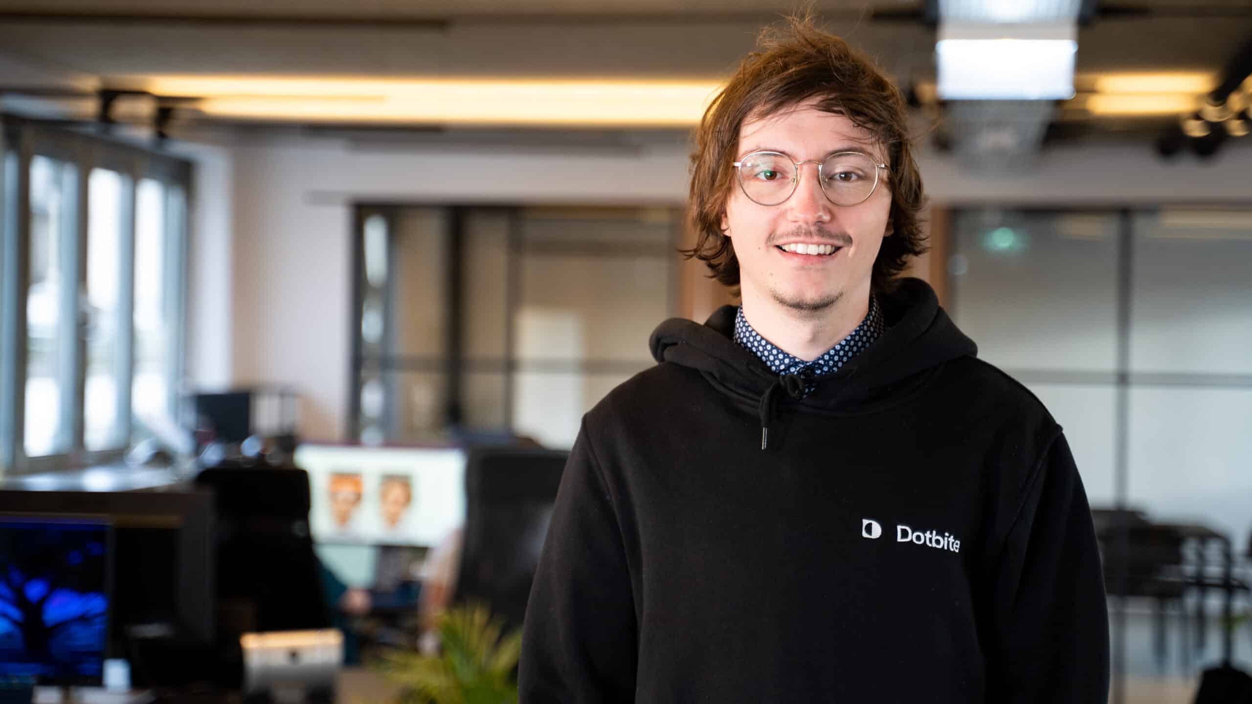 Senior Full Stack Developer is standing in the office and smiling